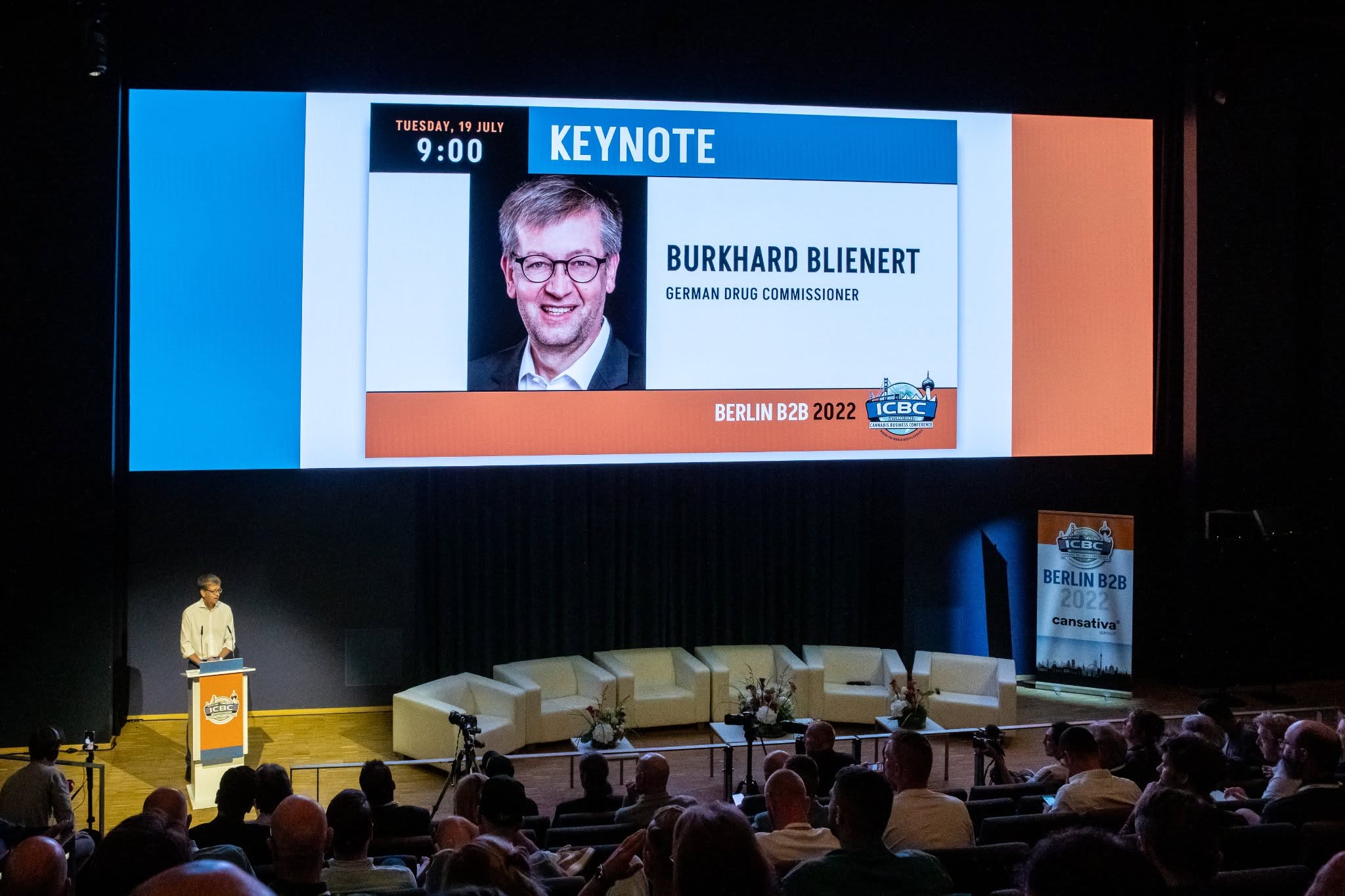 A trade fair stage with an audience. The large screen reads KEYNOTE and the name Burkhard Blienert, German Drug Commissioner, with ICBC's logo and the text Berlin B2B 2022.