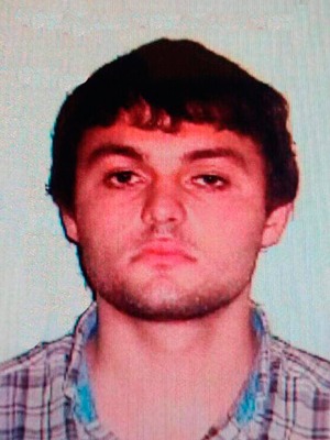 Portrait of a young man with dark hair and a checked shirt.