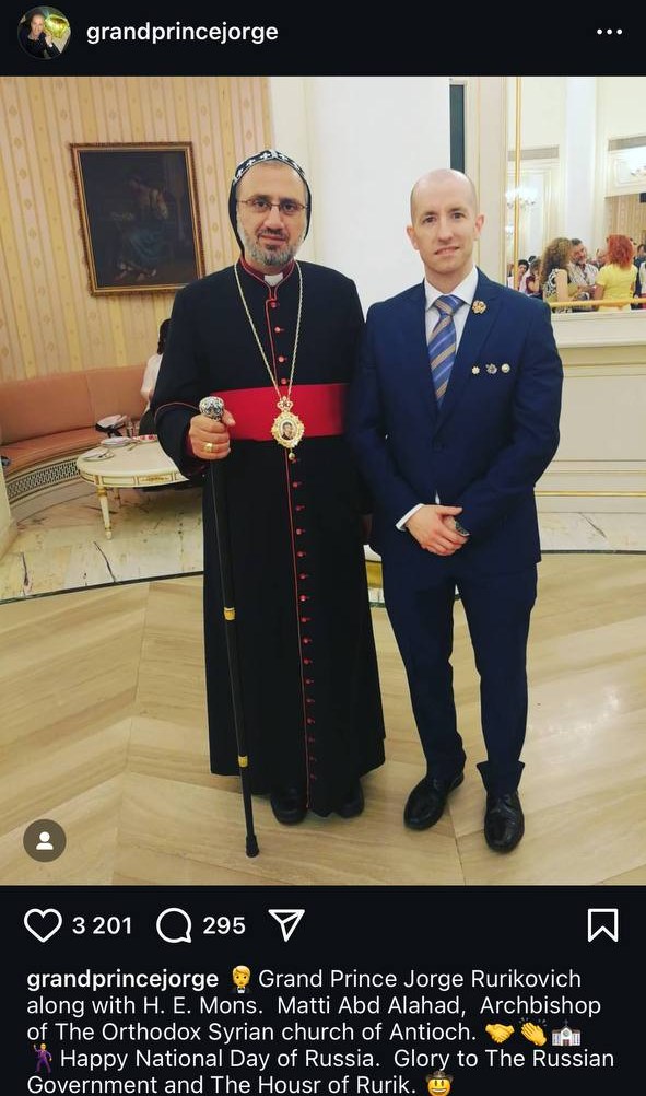 Screenshot of an Instagram post: a man in a suit next to an archbishop in a black robe with a red sash.